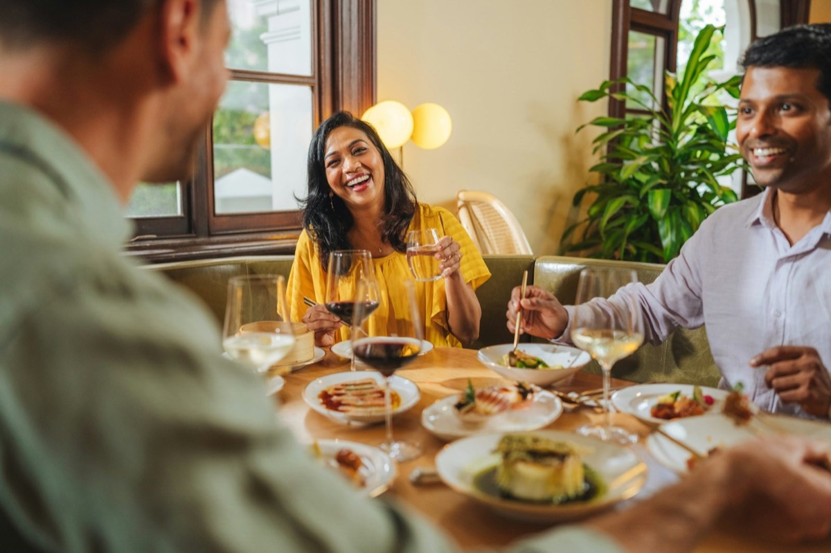 Friends laughing round a dinner table